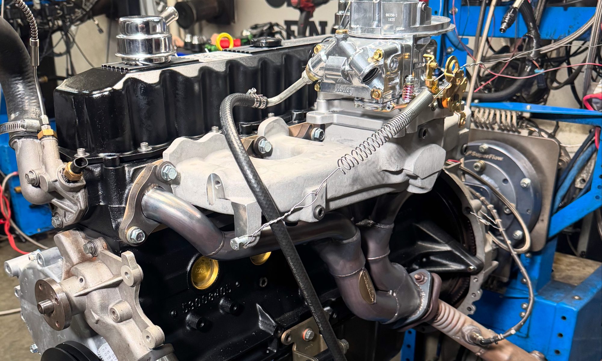 Jeep 4.0 stroker inline‑six engine running on a SuperFlow dyno stand, with headers, carb, and sensors hooked up for power testing.