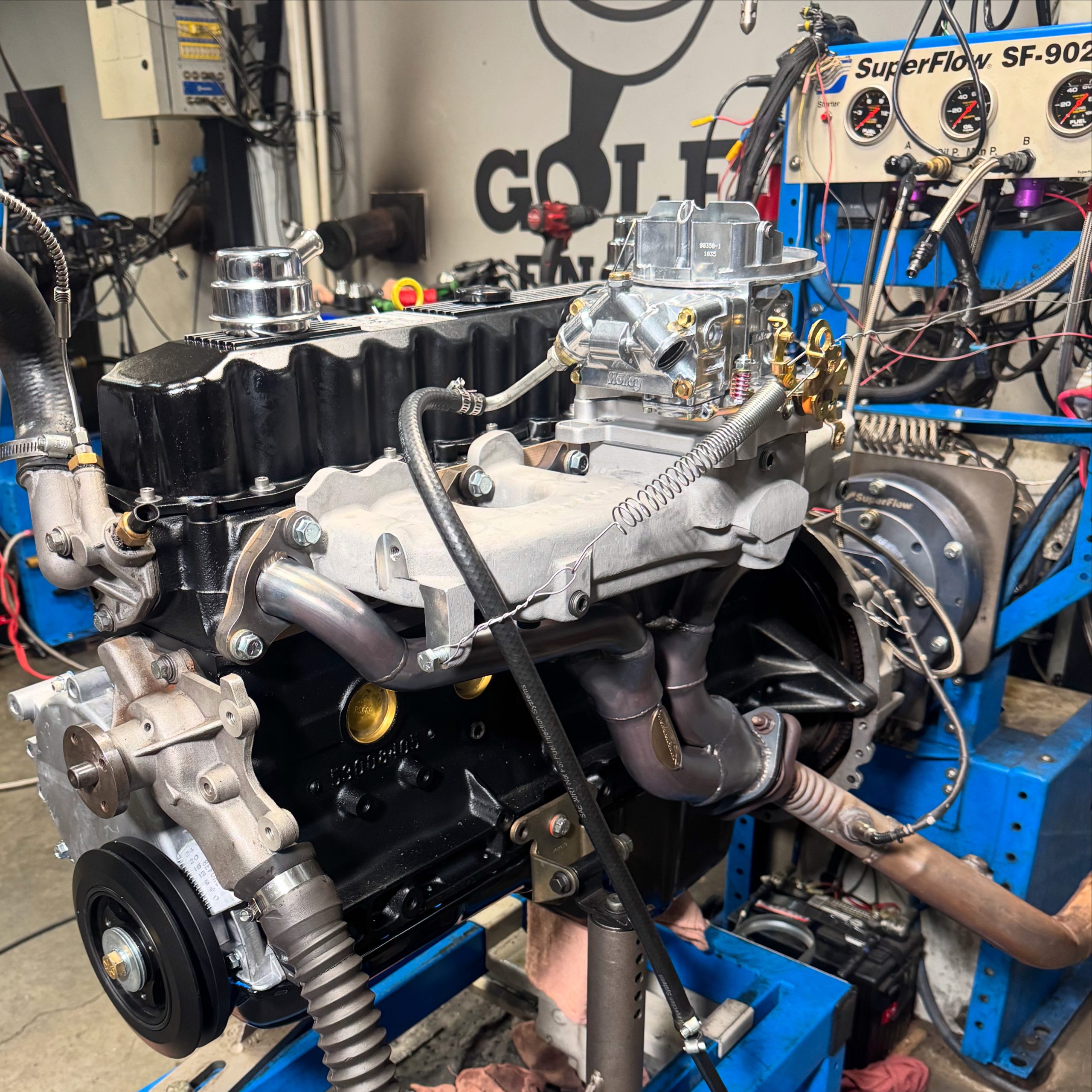 Jeep 4.0 stroker inline‑six engine running on a SuperFlow dyno stand, with headers, carb, and sensors hooked up for power testing.