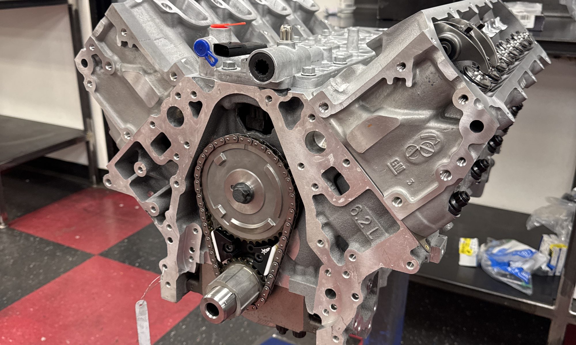 Aluminum Chevy small-block V8 crate engine on a stand in a clean engine shop, illustrating LT1 vs LT4 performance build differences.